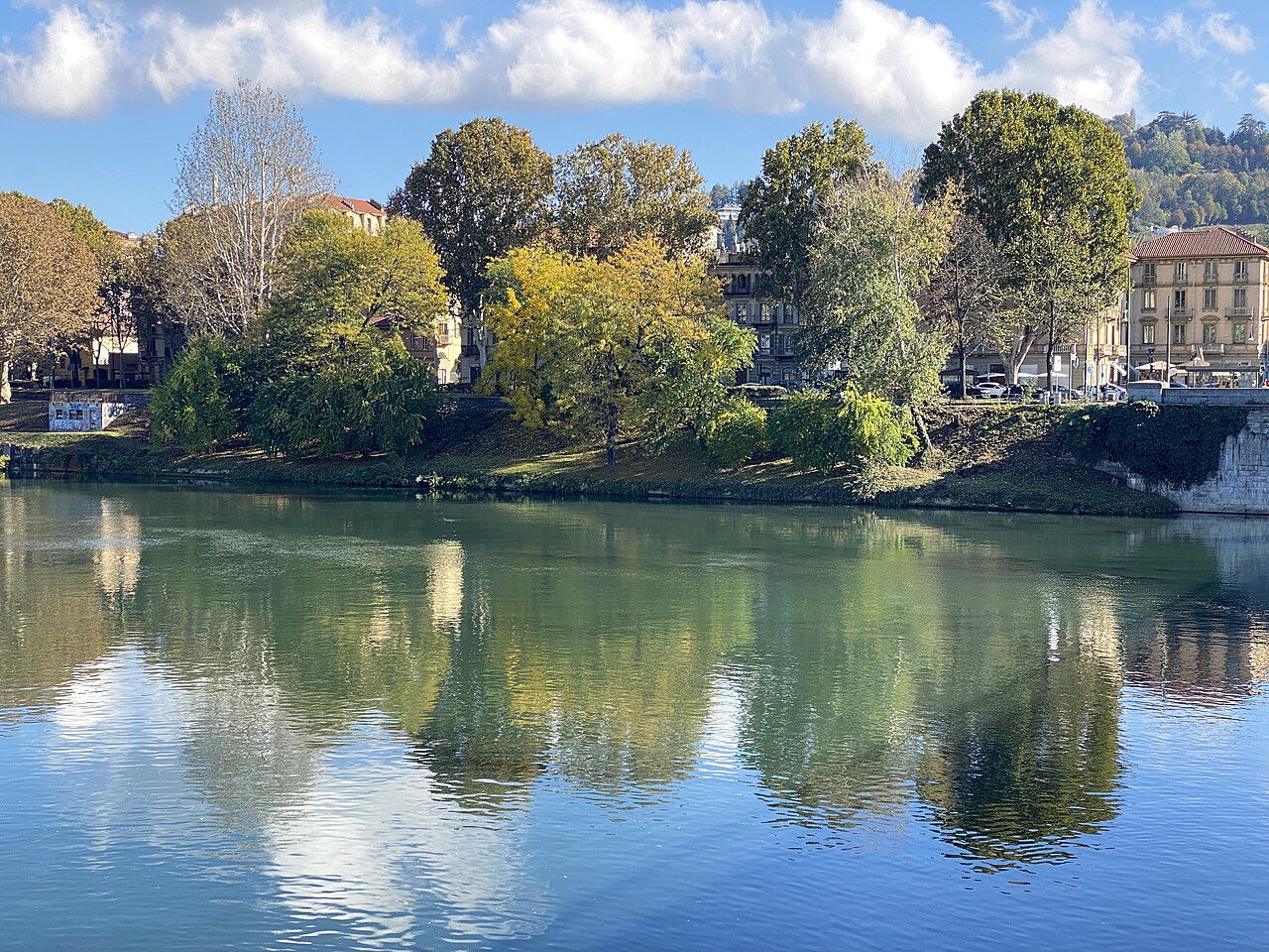 Il fiume Po attraversa Torino, con alberi e palazzi riflessi nell’acqua