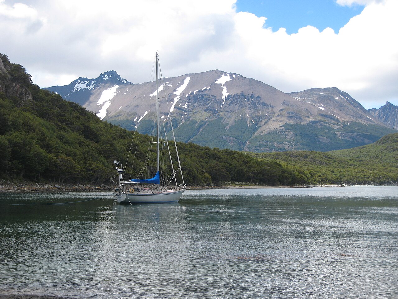 Una barca a vela nel canale di Beagle, davanti ai boschi e alle montagne del Parco nazionale Tierra del Fuego